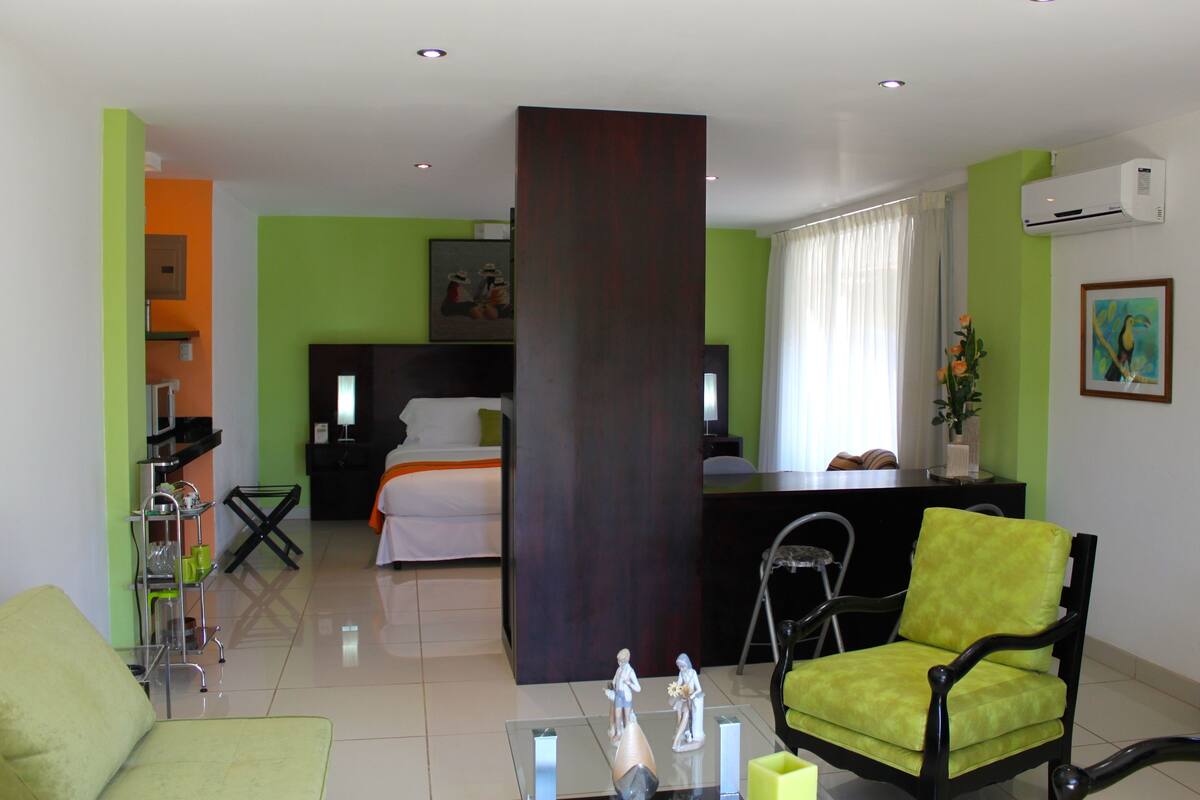 Una habitación de hotel con cama, escritorio, silla, sofá y mesa de centro.