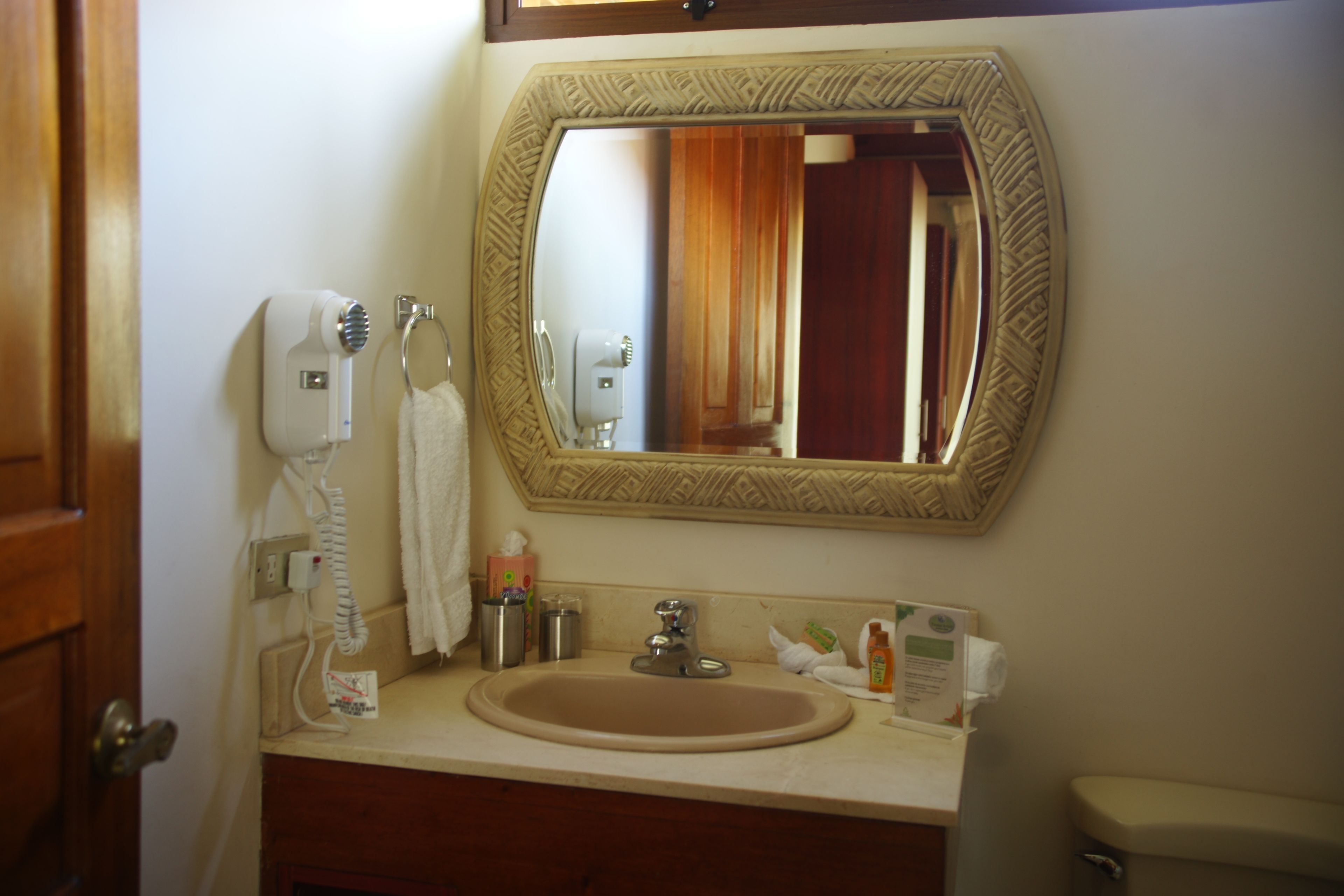 A bathroom with a sink, mirror, towel dispenser, and toilet.