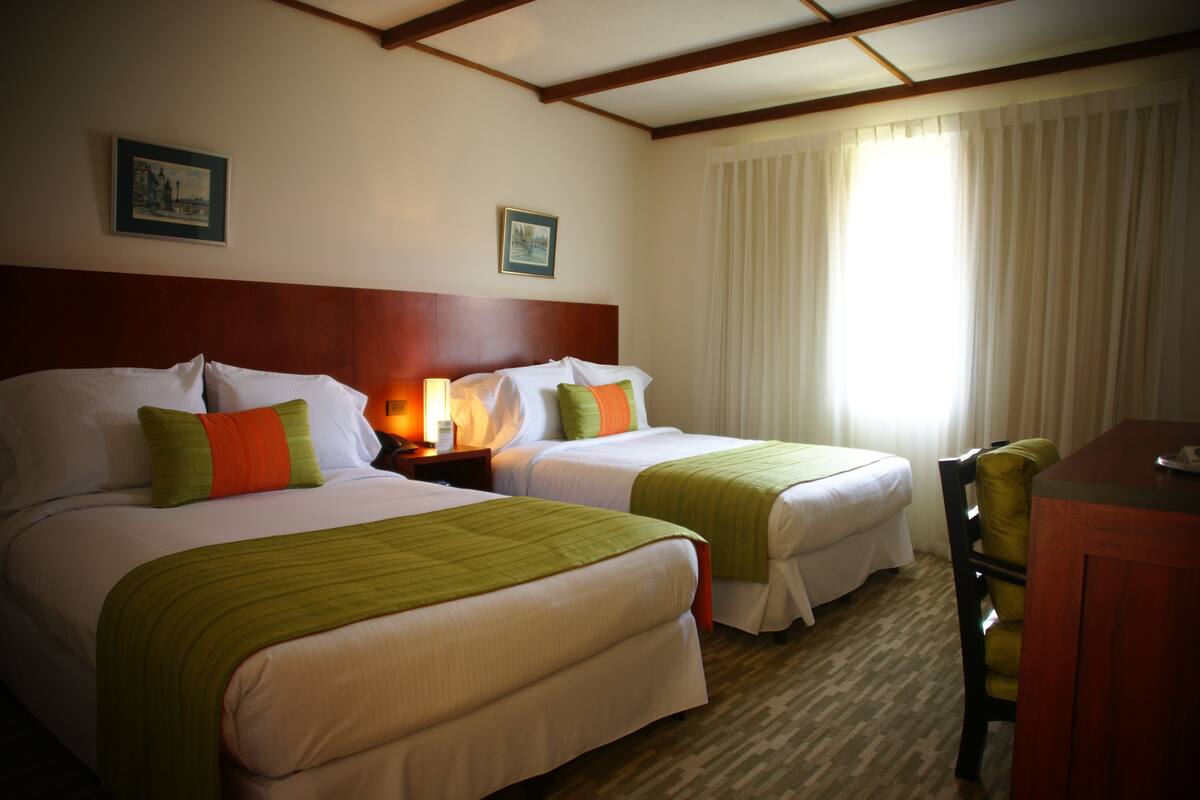 Habitación de hotel con dos camas, un escritorio y una silla.