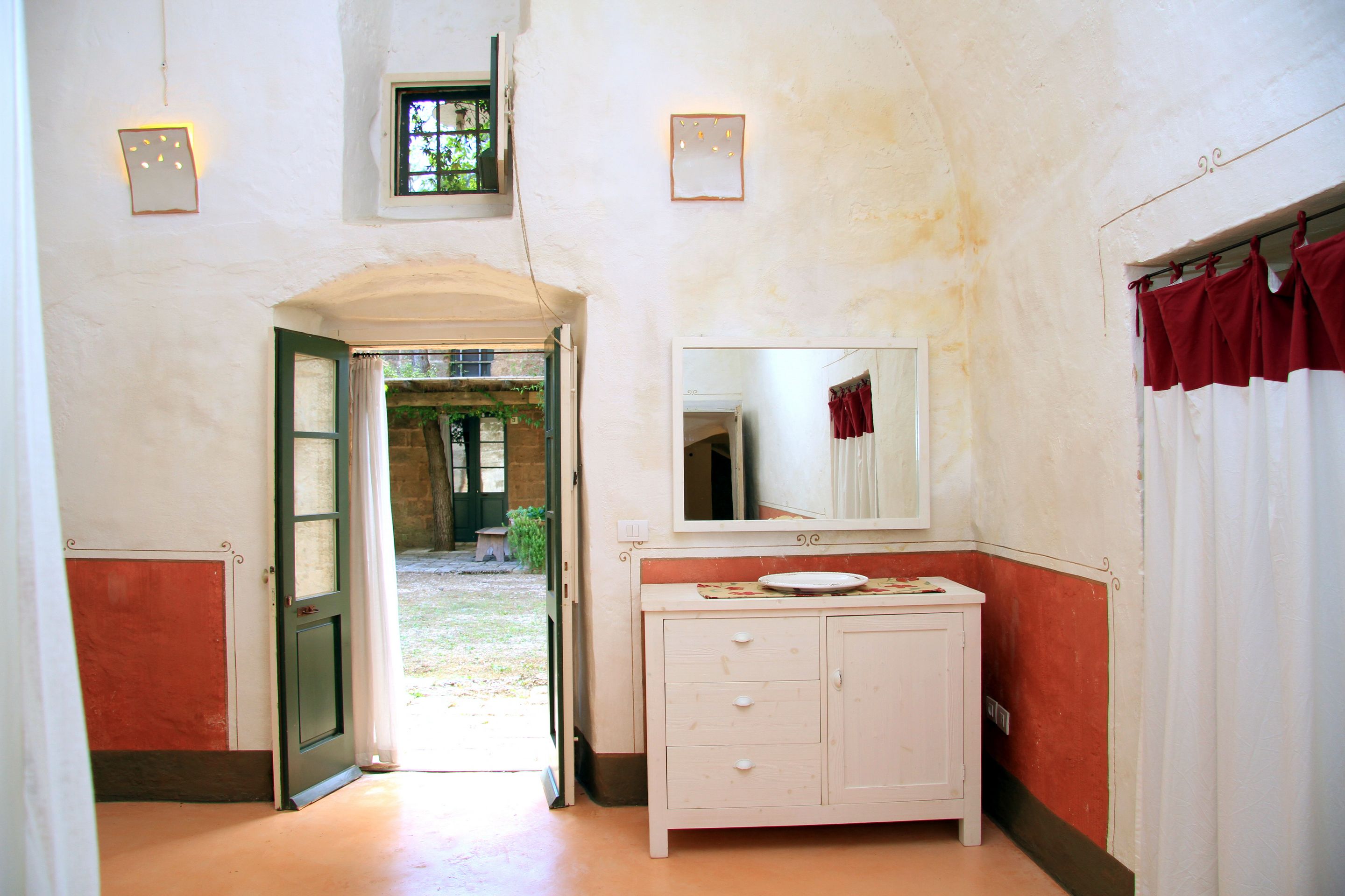 A narrow hallway with a white vanity, a mirror, and a door leading to an outdoor area.