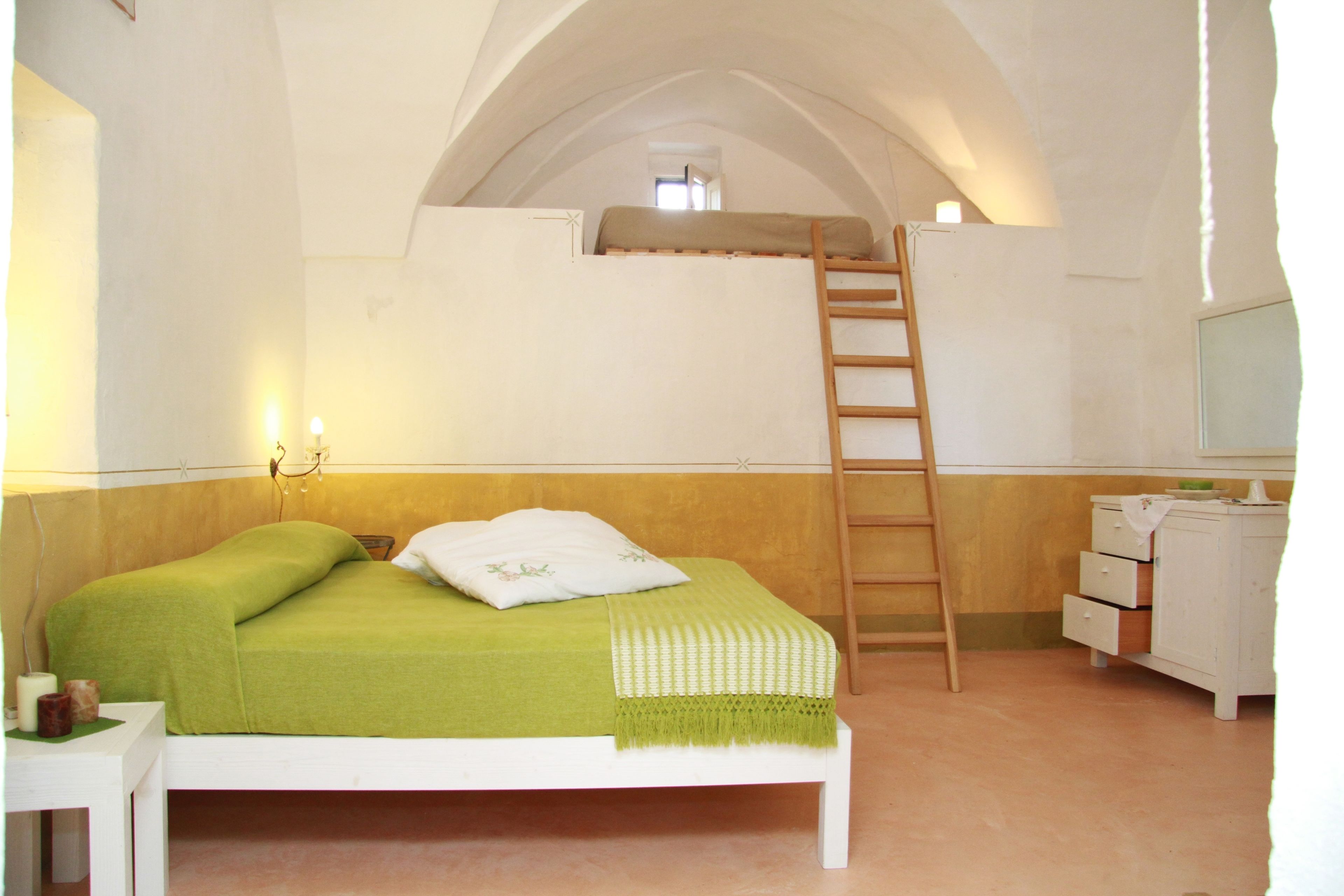 Quarto com cama beliche, escada, mesa de cabeceira e cômoda.