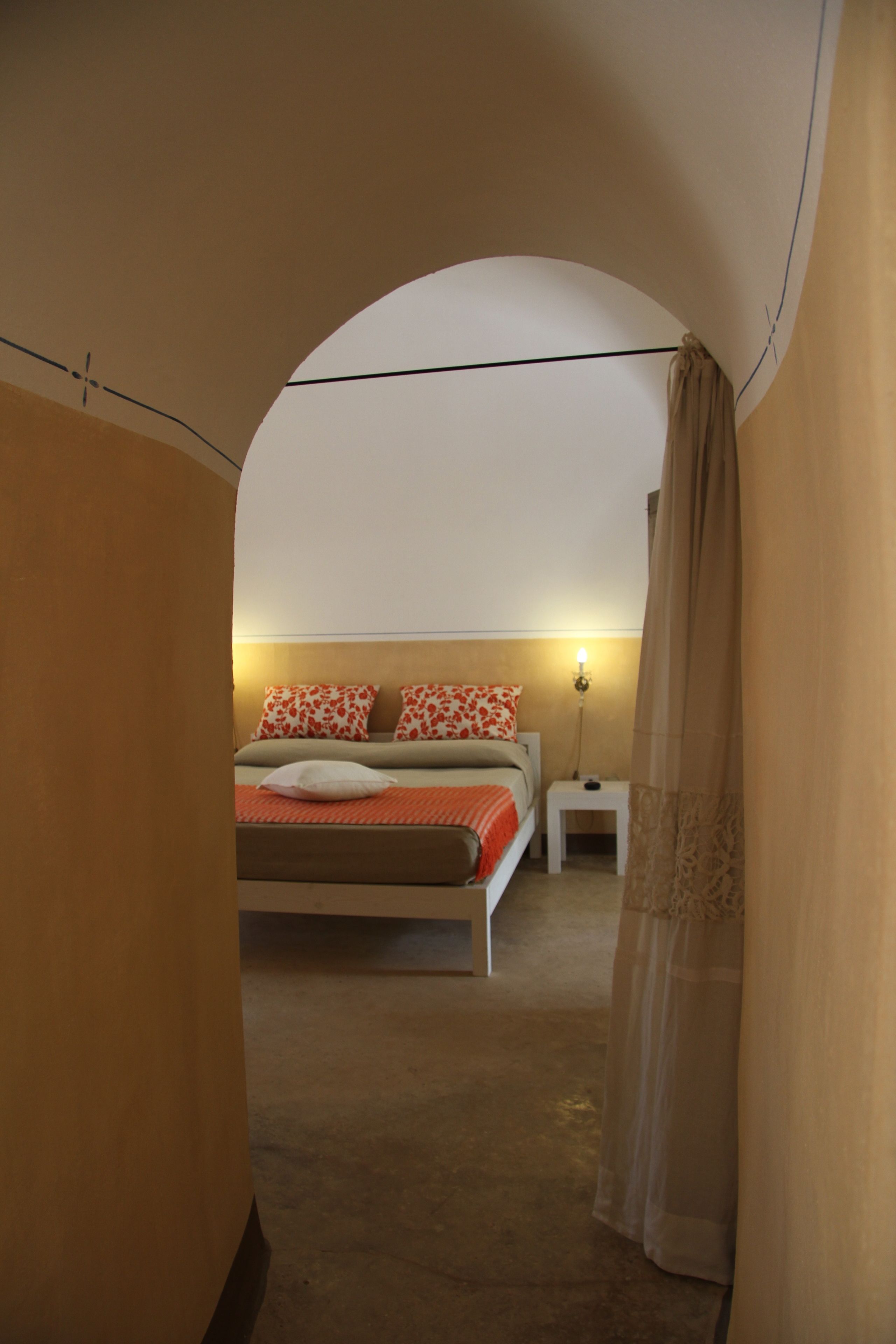 Une chambre à coucher avec un lit, des oreillers, une table de chevet et une lampe.