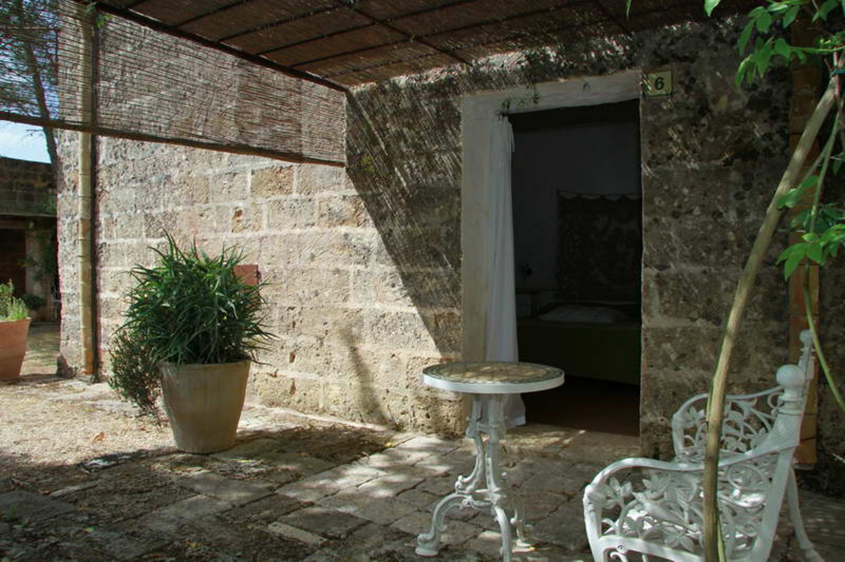 A stone-walled courtyard with a potted plant, a small table, and a bench.