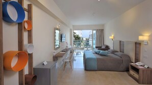 Habitación de hotel moderna con cama, escritorio, sillas, un balcón con vistas y un televisor montado en la pared.