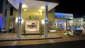 Entrada de un hotel con mostrador de recepción, asientos exteriores y zona de piscina.