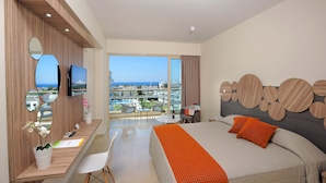 Una habitación de hotel moderna con una cama grande, un escritorio con computadora, un televisor y un balcón con vistas a la ciudad.