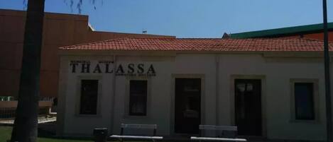 A building labeled "Municipal Museum Thalassa" with a tiled roof, benches, and a trash can in front.