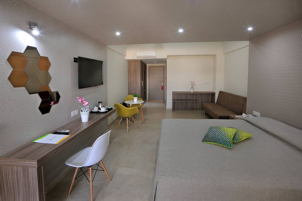 Une chambre d’hôtel moderne équipée d’un bureau, d’un lit, d’un canapé et d’une télévision.