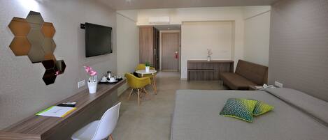 Una habitación de hotel moderna con escritorio, cama, sofá y televisión.