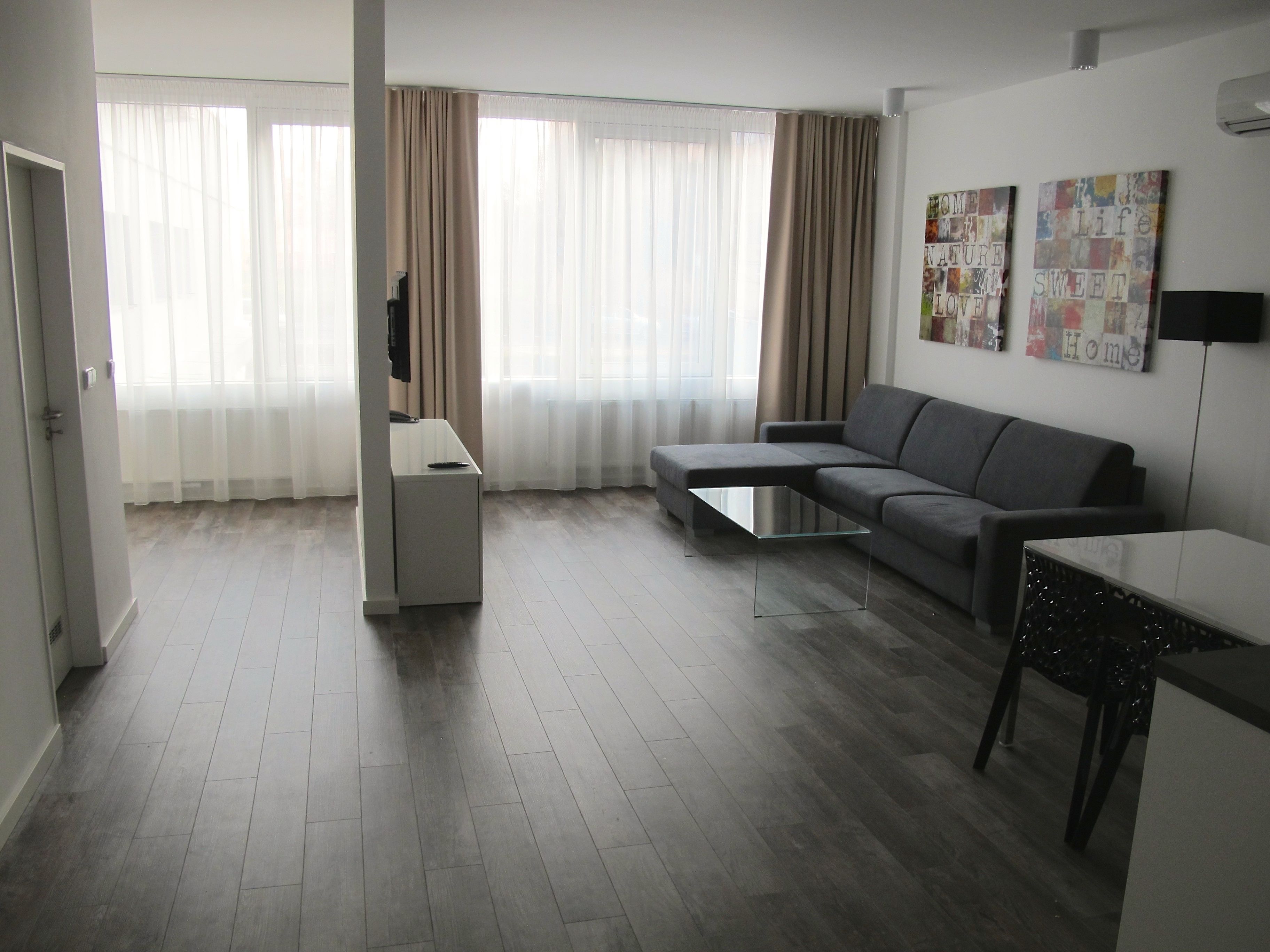 A modern living room with a grey sofa, a glass coffee table, and a flat-screen TV.