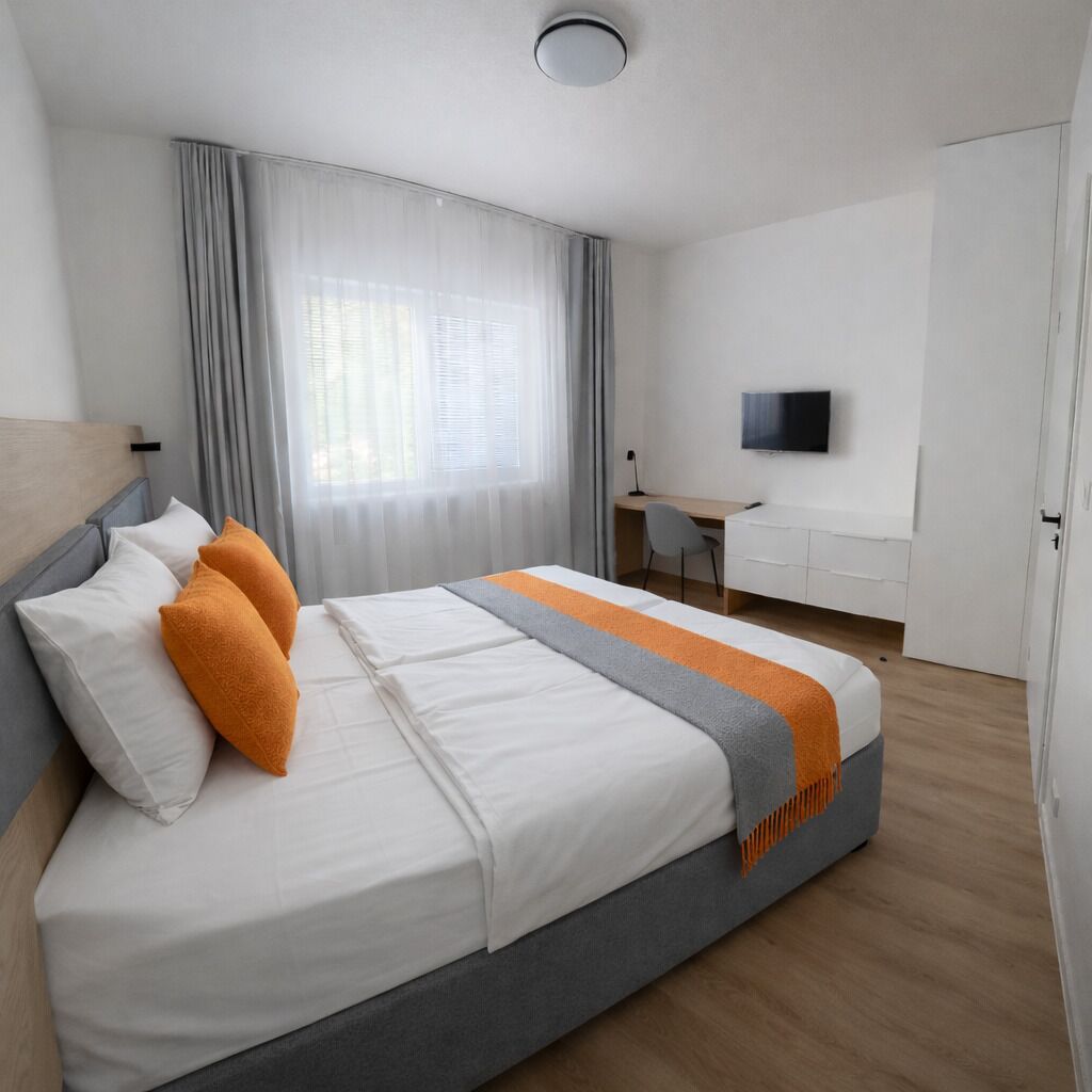 A modern hotel room with a large bed, a desk, and a television.