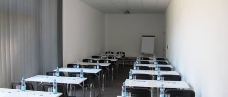 A conference room with rows of tables, chairs, and water bottles.