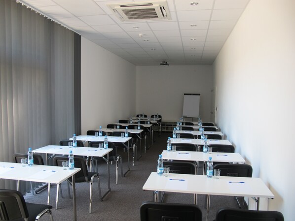 A conference room with rows of tables, chairs, and water bottles. - Hotel Kapitol (Most)