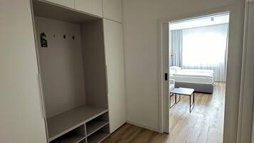 Una habitación con un vestidor amplio, una cama con cabecera blanca y una mesita pequeña.