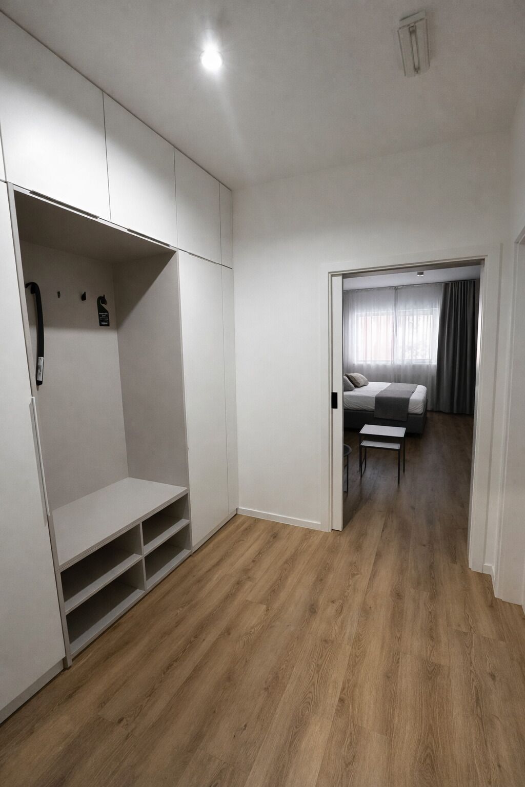 A modern bedroom with a large closet, a bed, and a small table.