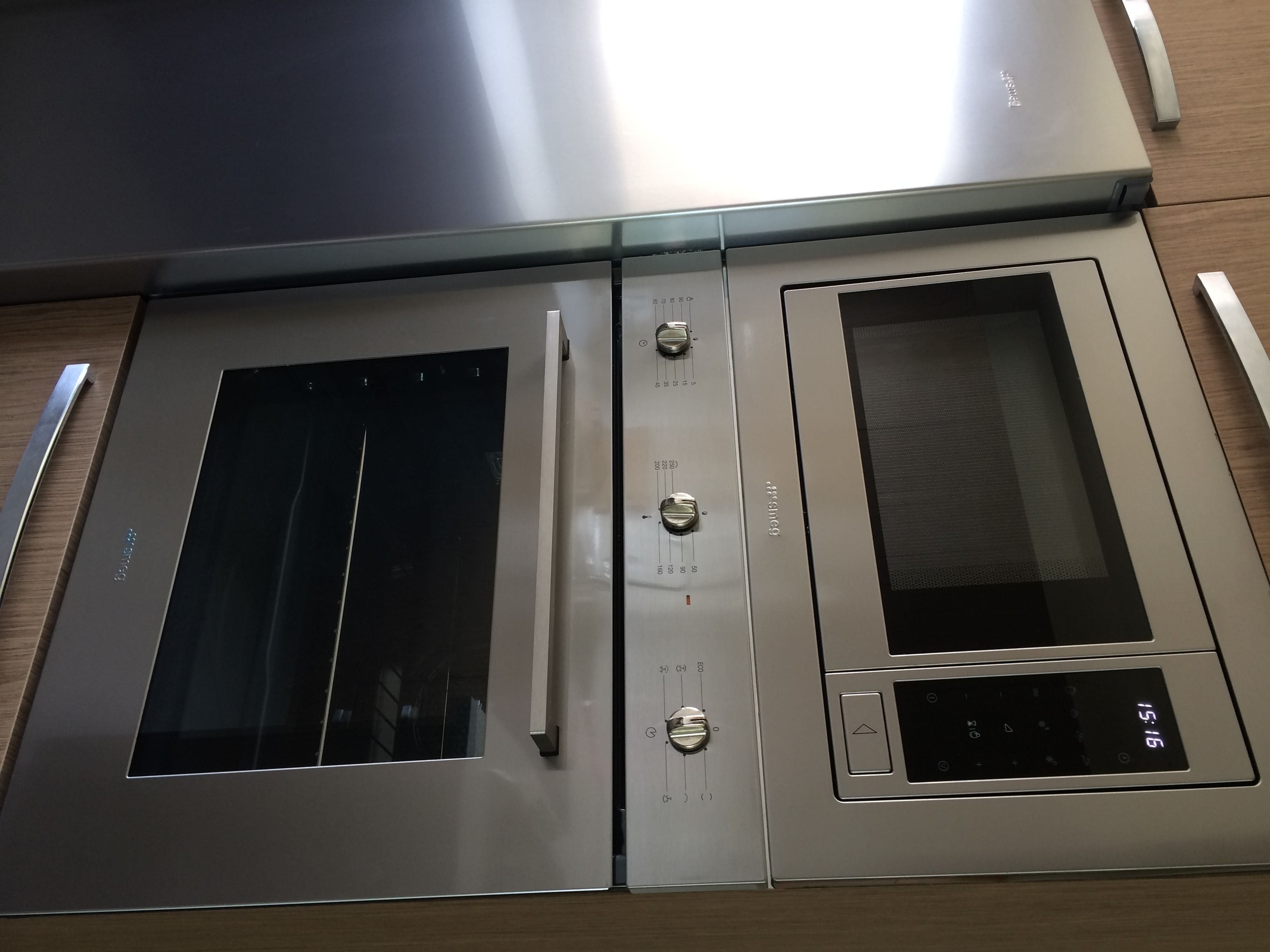A stainless steel double oven with a digital clock display, a handle, and a control panel with knobs.