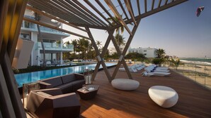A wooden deck with lounge chairs and a pool. - Ultravioleta Boutique Residences (Cabarete)