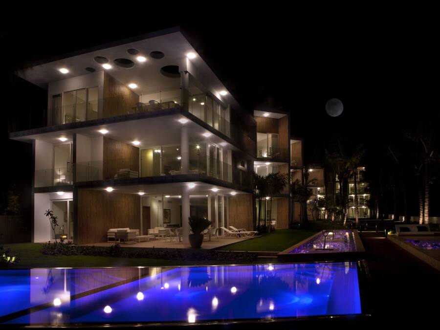 A modern multi-story hotel with a pool area, outdoor seating, and a view of the moon.