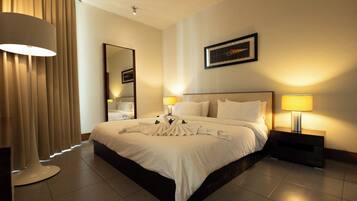 A hotel room with a large bed, two bedside lamps, a mirror, and a framed picture on the wall.