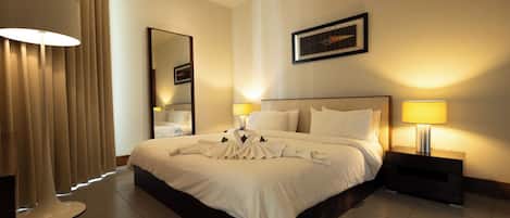 A hotel room with a large bed, two bedside lamps, a mirror, and a framed picture on the wall.