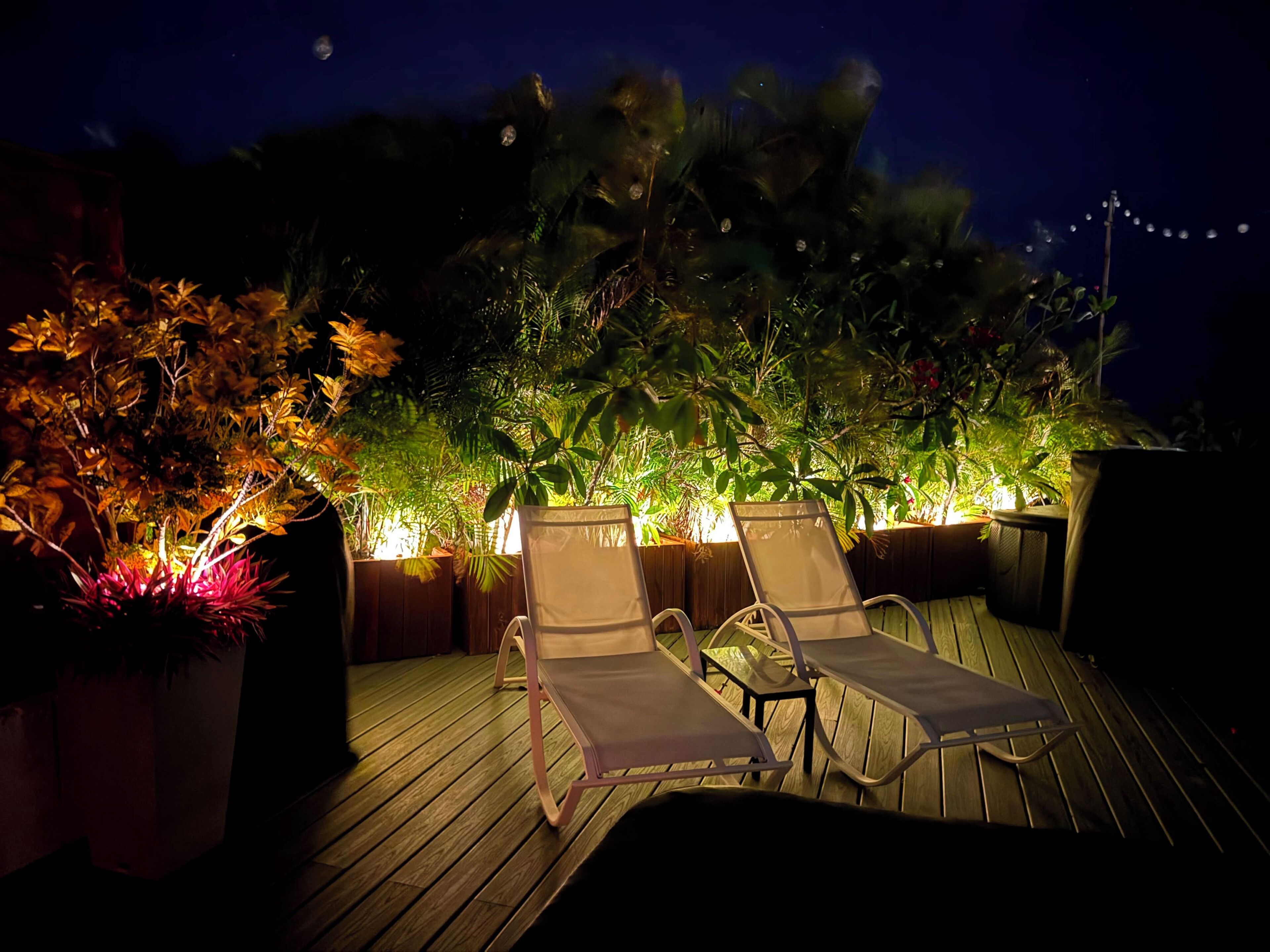 An outdoor deck with two lounge chairs and a wooden floor.