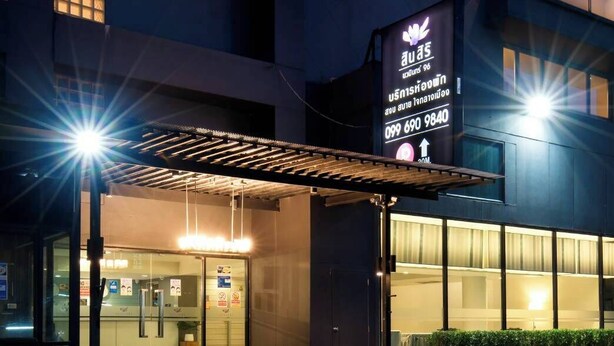 Un edificio moderno con entrada cubierta y un cartel que muestra información de contacto.