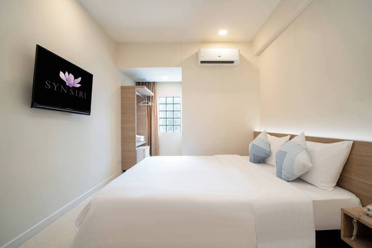 Une chambre d’hôtel équipée d’un lit, d’un téléviseur fixé au mur et d’un appareil de climatisation.
