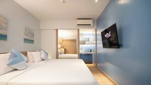 Habitación de hotel con una cama grande, un televisor de pantalla plana montado en la pared y un baño visible a través de una puerta abierta.
