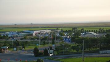 A view of an airport with a large terminal building, a control tower, and surrounding green fields.