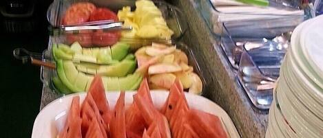Un bufé con diversas frutas y verduras, como sandía, plátanos y zanahorias.