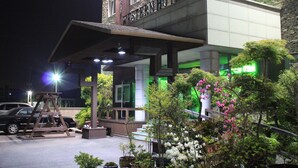 Hotel Western com entrada coberta, área de estar externa e vasos de plantas.