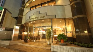 A hotel entrance with glass doors, potted plants, and a tiled exterior.