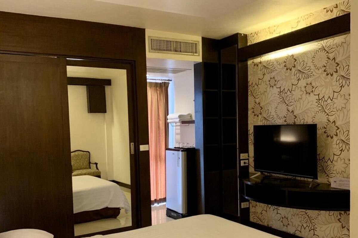A hotel room with a bed, a television, a minibar, and a bathroom visible through an open door.