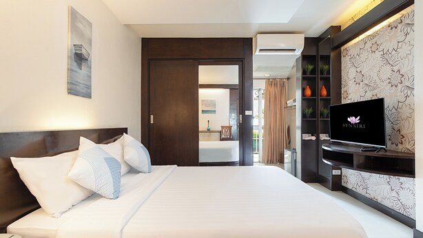 Een hotelkamer met een bed, een televisie, een telefoon en een badkamer, zichtbaar door een geopende deur.