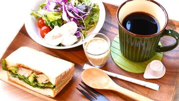 A meal tray with a sandwich, salad, cup of coffee, and a spoon.