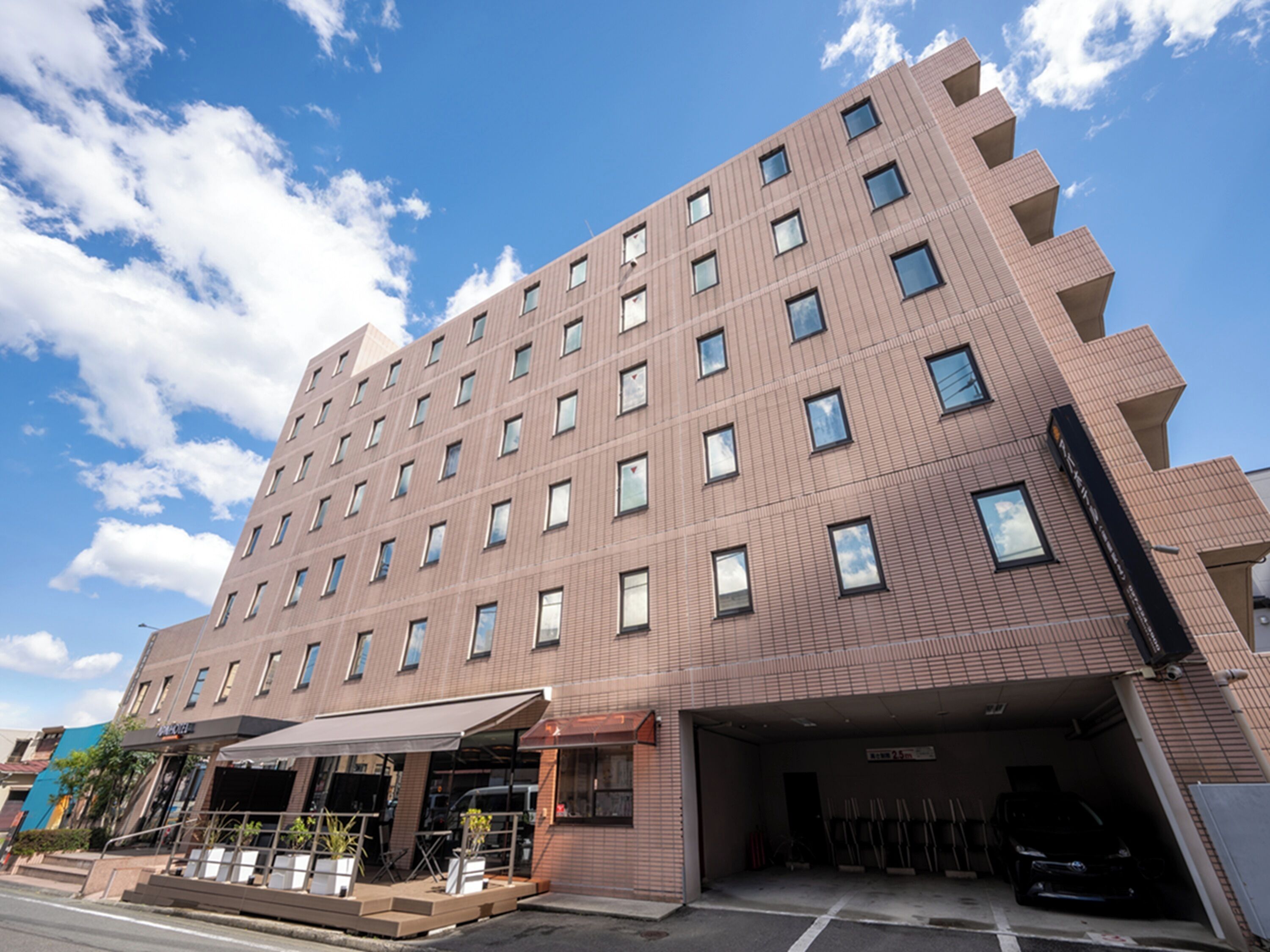 A multi-story hotel with a modern architectural design, featuring a flat roof and a series of windows on each floor.
