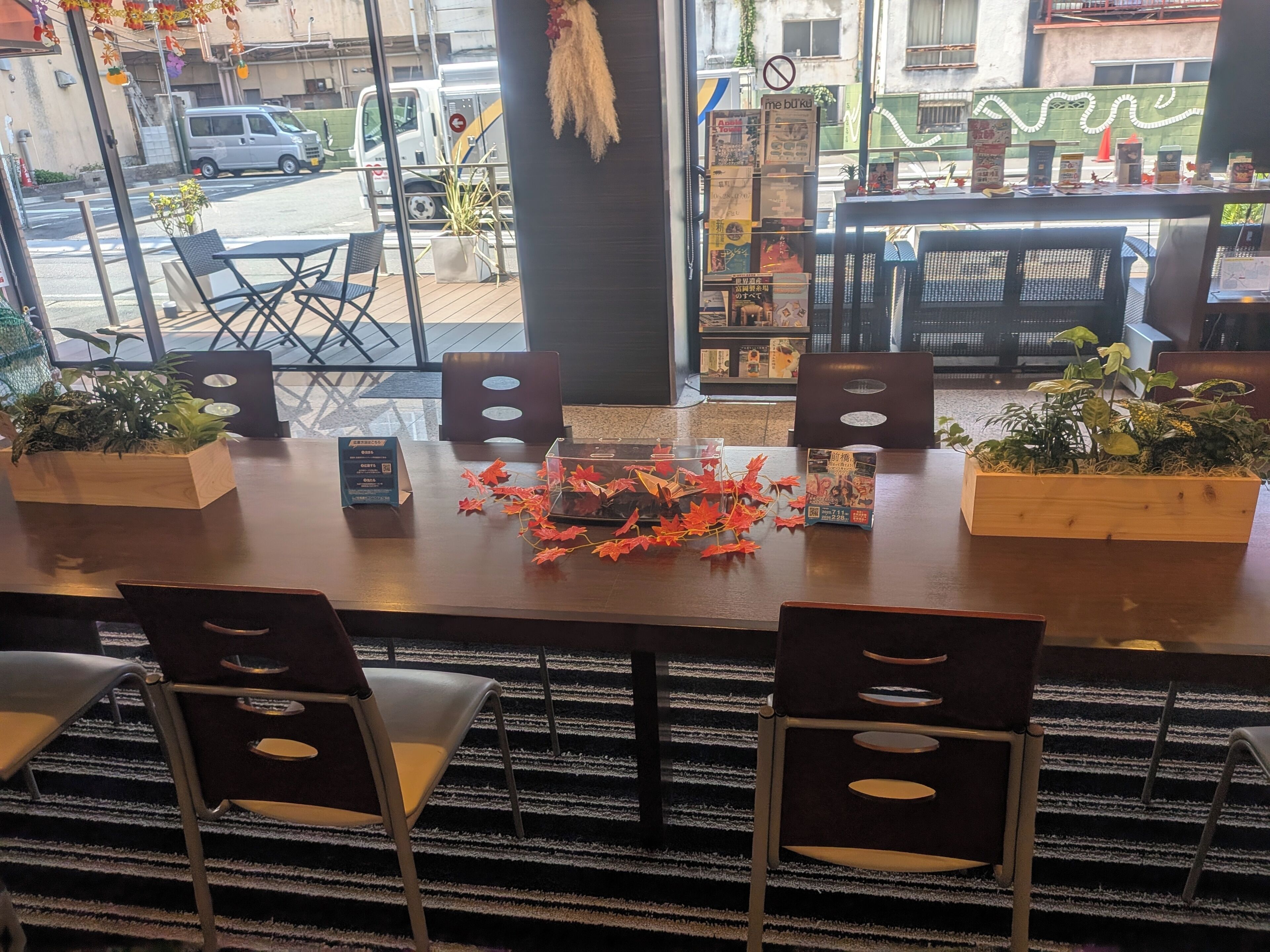 Un interior de restaurante con una mesa de madera, sillas y plantas en macetas.