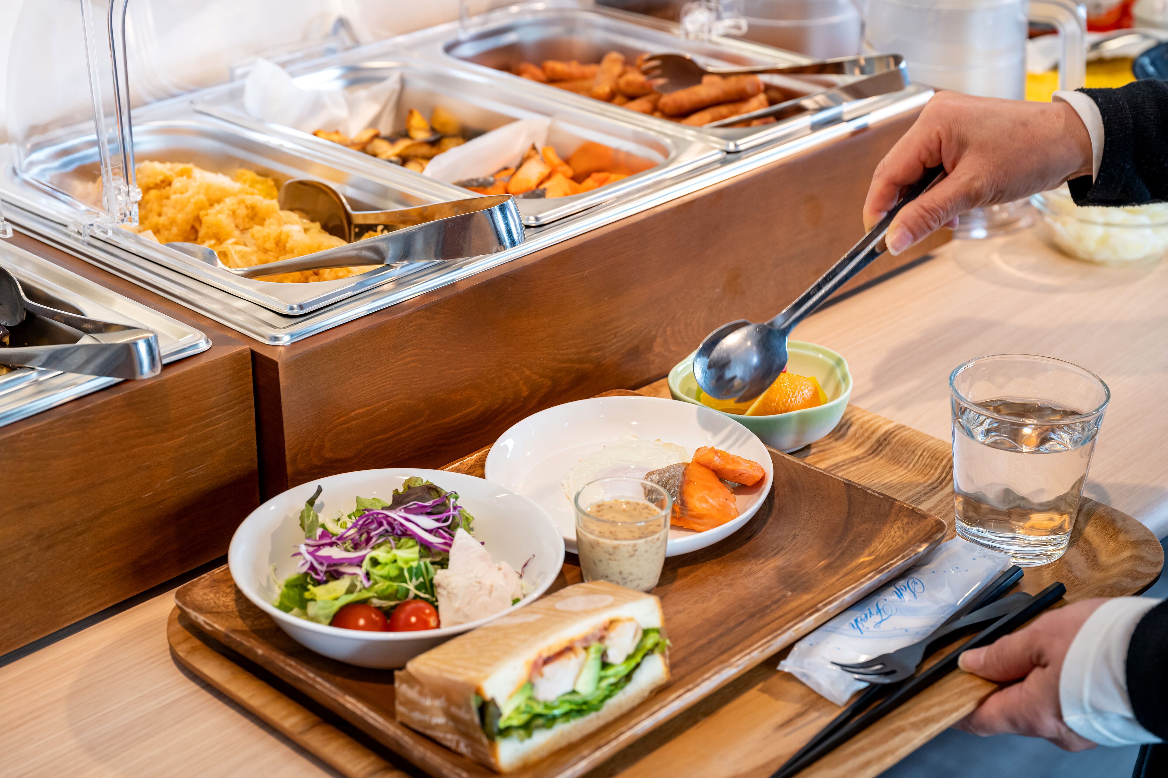 A buffet setup with various food items and a person serving food.