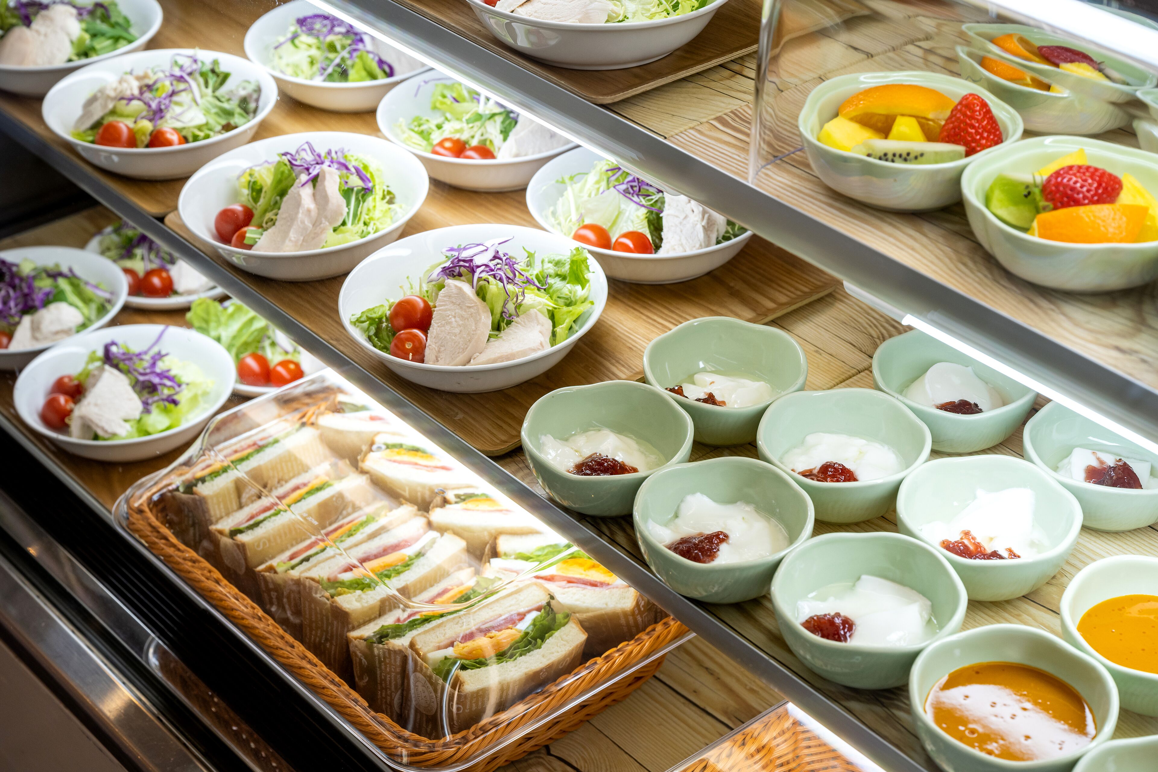 A buffet with various food options including salads, sandwiches, and fruit bowls.