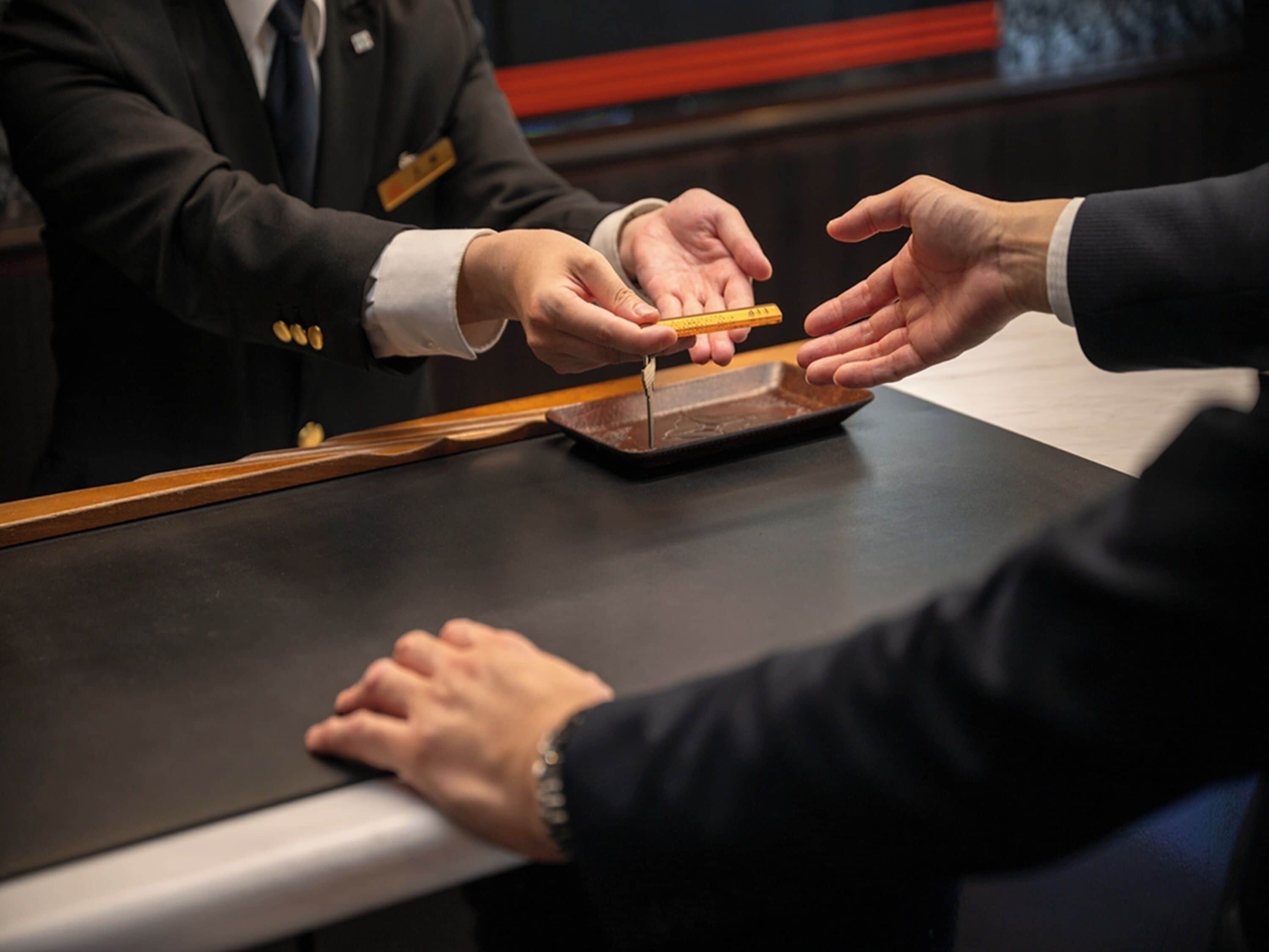 A person handing over a tray with a yellow object to another person at a counter.
