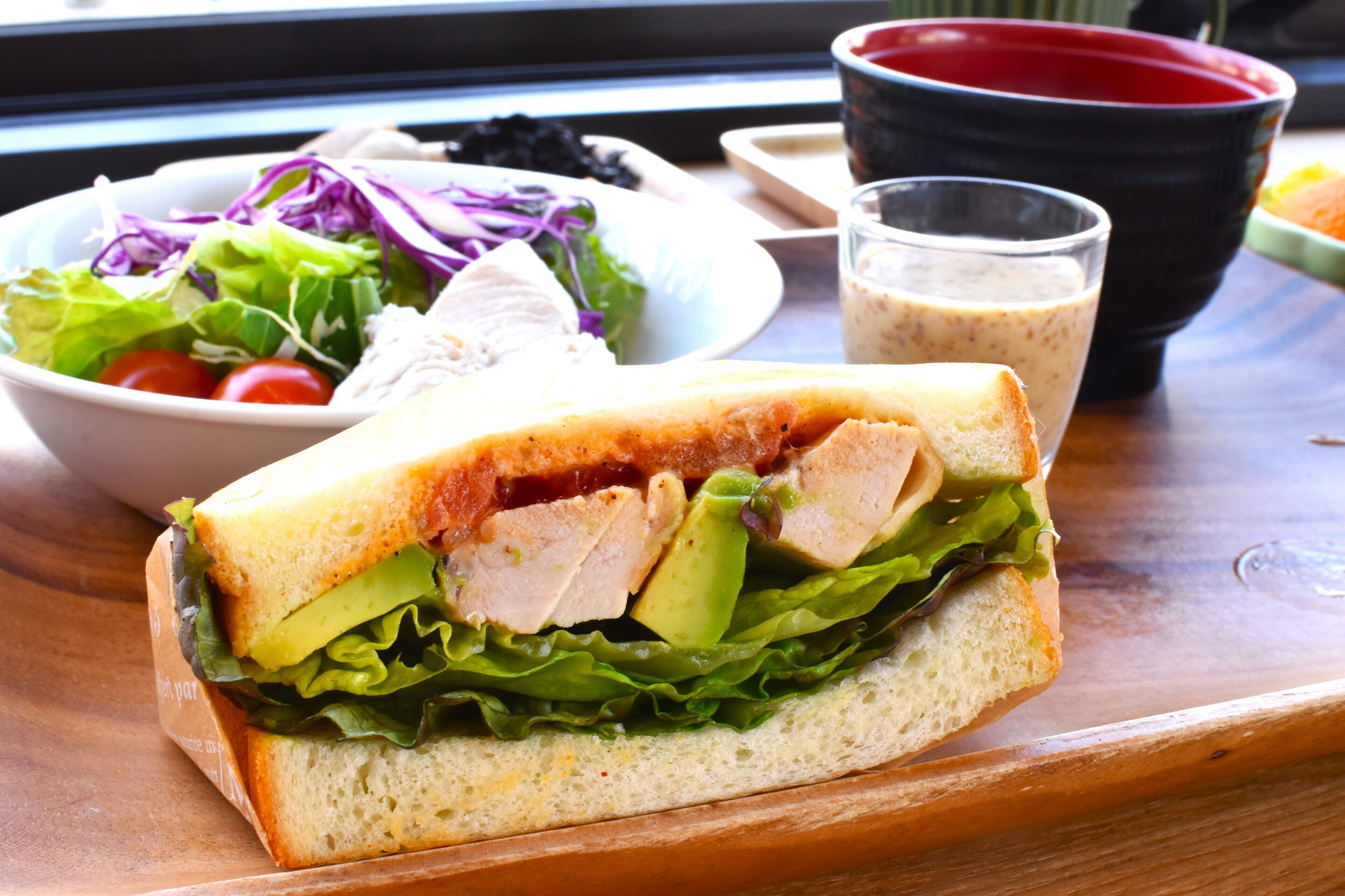 Sándwich de lechuga, tomate y pollo sobre una tabla de madera.