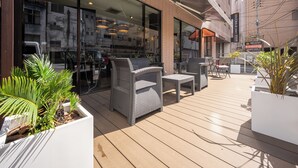 An outdoor seating area with wicker furniture and potted plants. - APA Hotel Maebashieki-Kita (Maebashi)