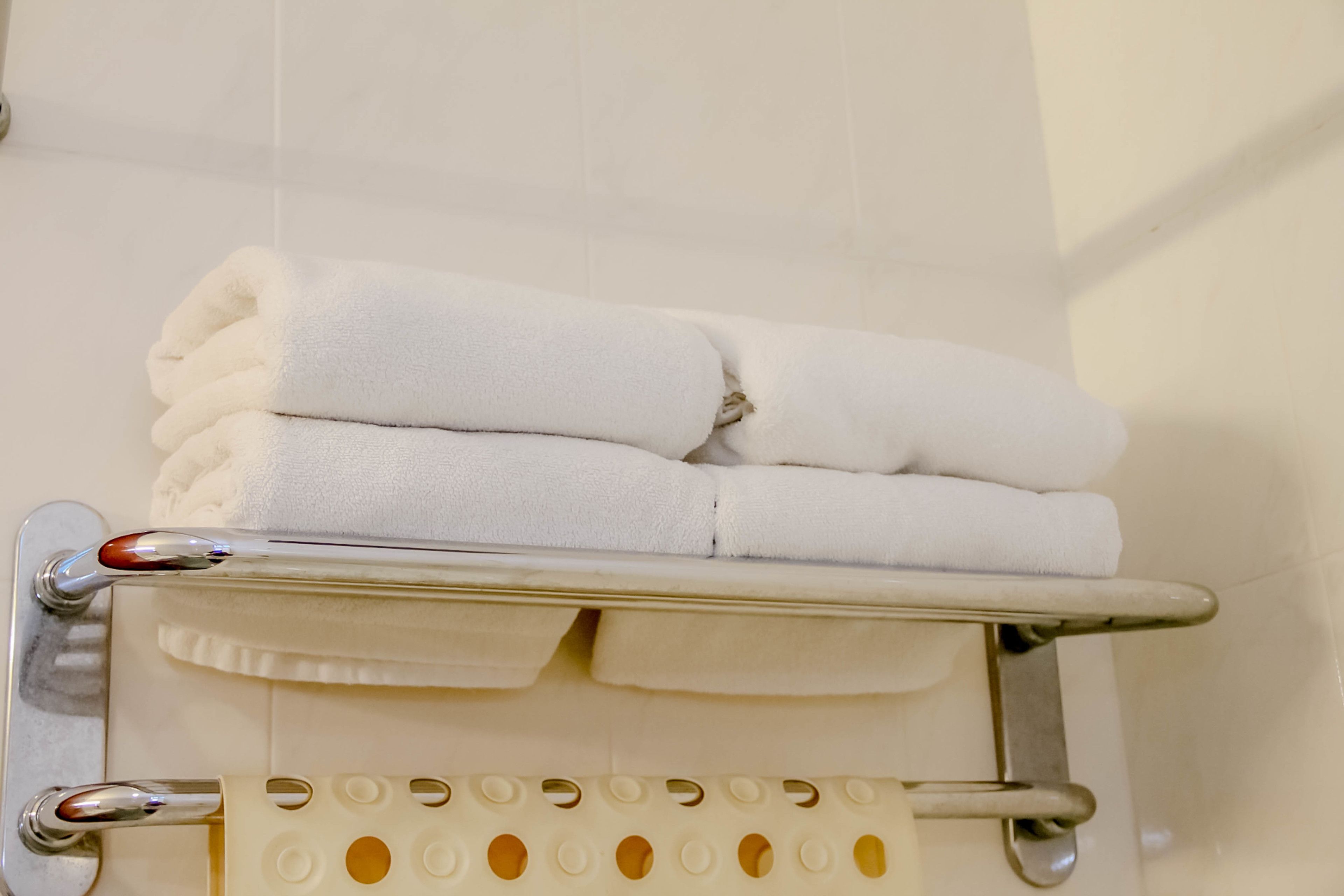 A bathroom with a towel rack holding folded towels and a toilet paper holder.