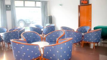 A room with several blue chairs with orange trim, a white table, and a green couch. There is a door labeled "Tiger" and a window with curtains.