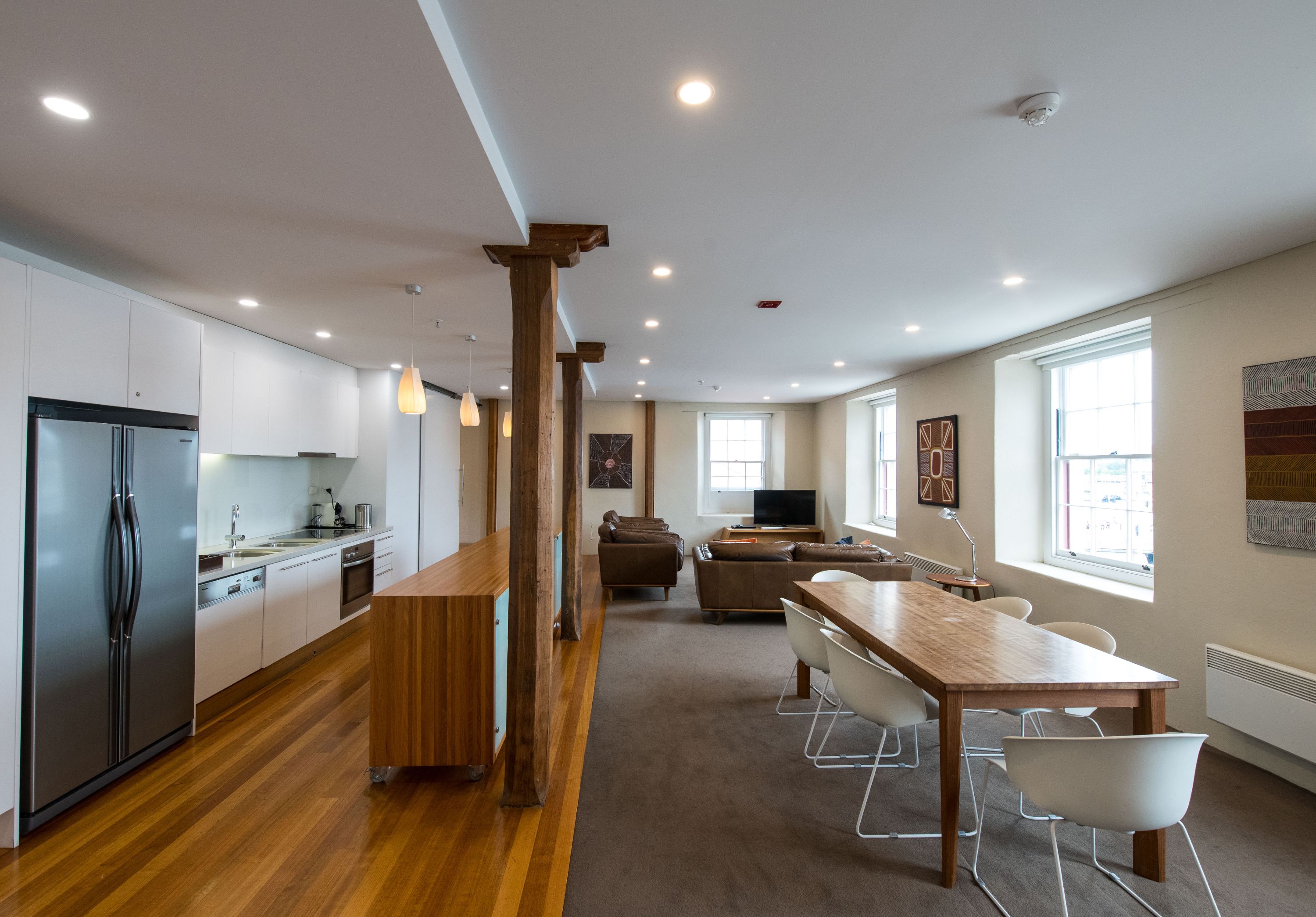 A modern kitchen with built-in appliances, a wooden dining table, and a cozy seating area with a sofa and chairs.