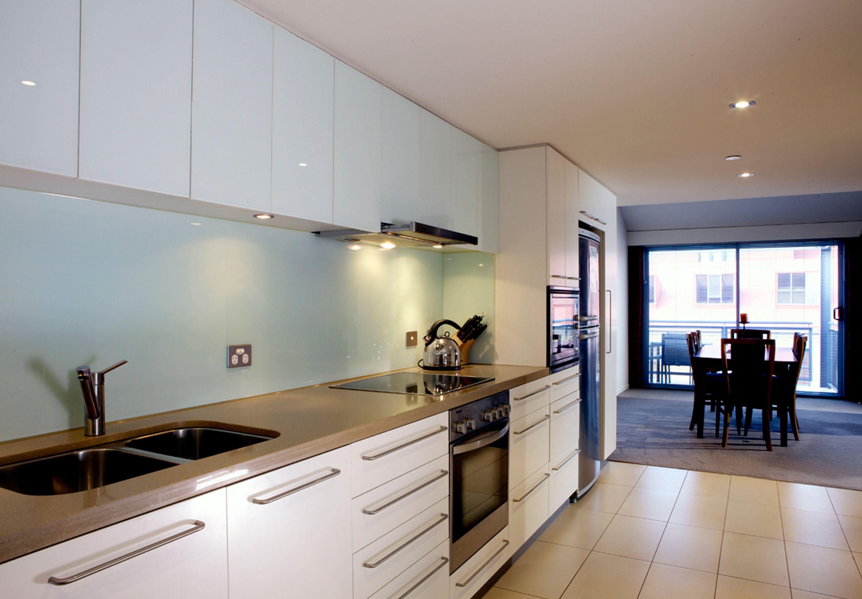 A modern kitchen with stainless steel appliances, a double sink, and a dining area with a table and chairs.