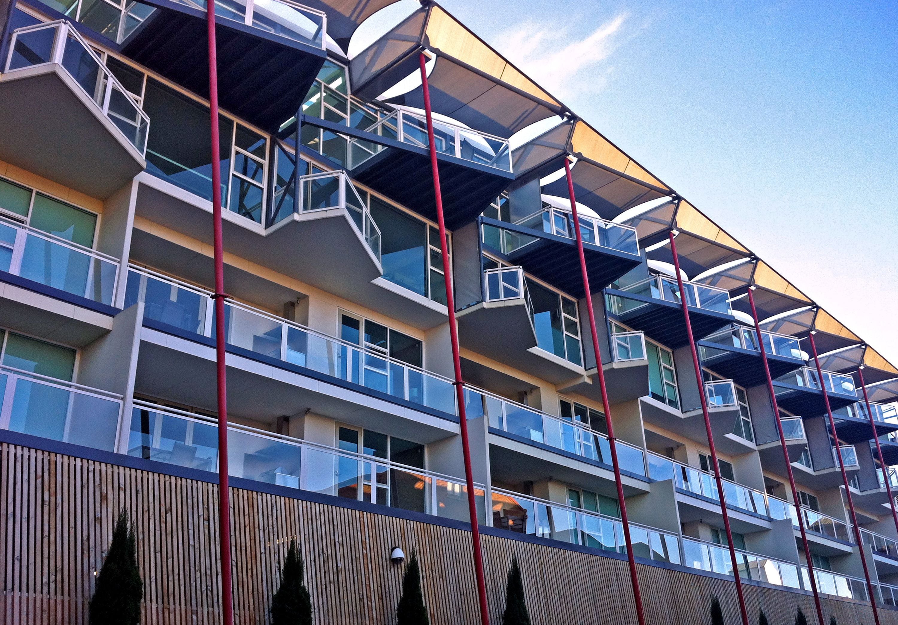 Un hôtel à plusieurs étages doté de balcons, de grandes fenêtres et d’une architecture moderne.
