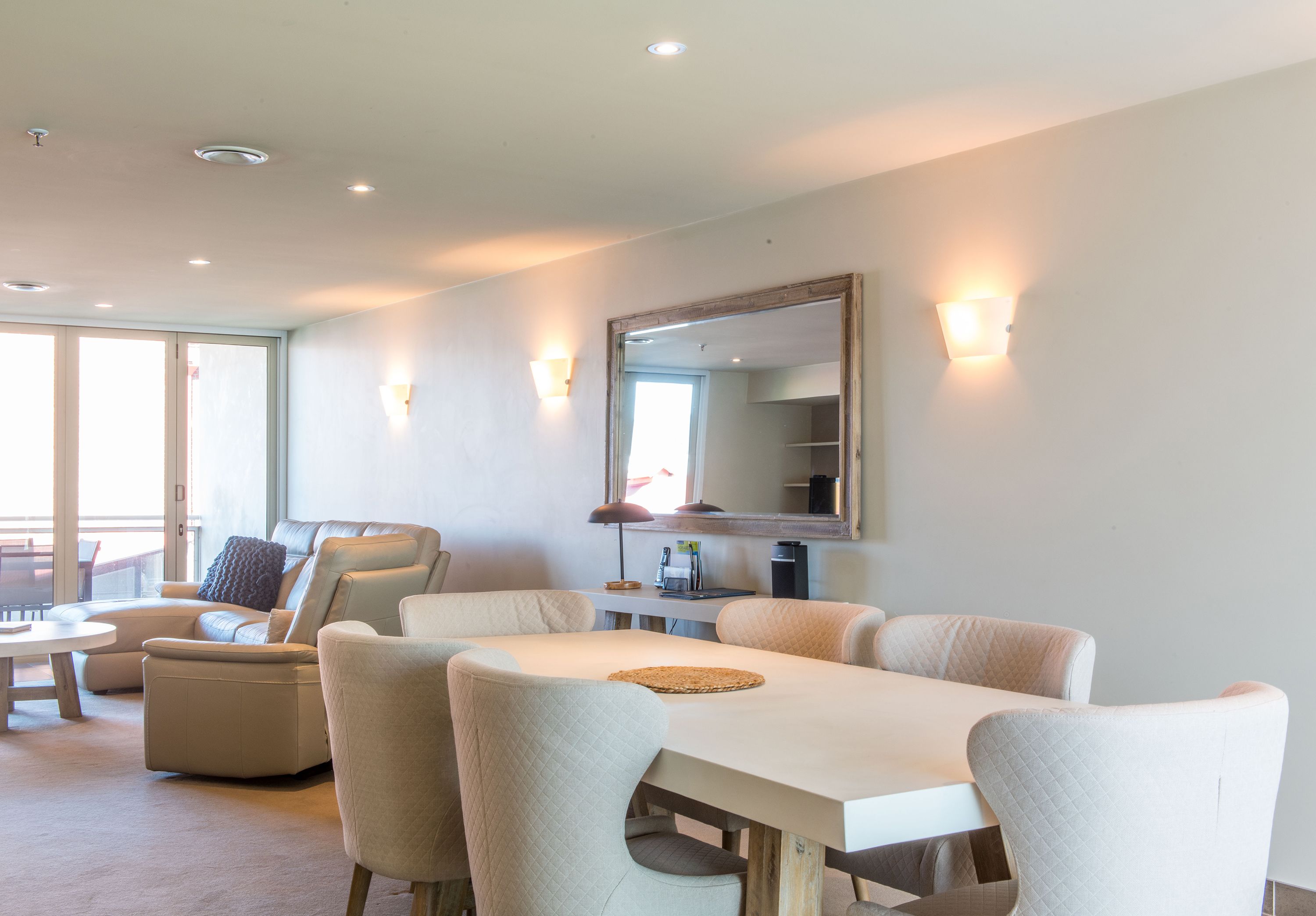 A spacious living area with a dining table, comfortable seating, and a large mirror.