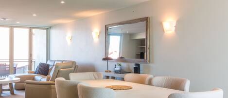 A spacious living area with a dining table, comfortable seating, and a large mirror.