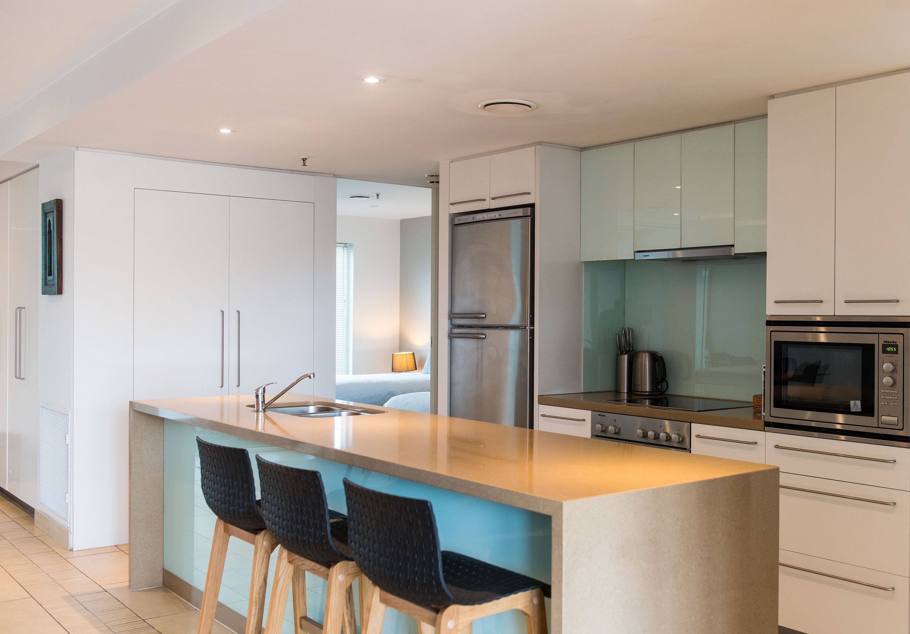 A modern kitchen with a central island, stainless steel appliances, and bar stools.